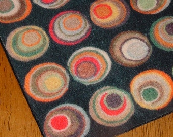 May include: A black rug with a repeating pattern of colorful concentric circles. The circles are in shades of brown, green, orange, red, and yellow.