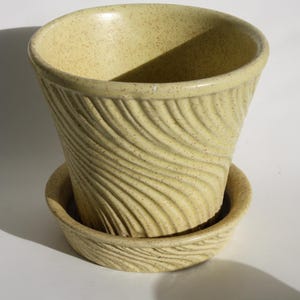 Peut inclure: Un pot de fleur en céramique jaune clair avec une soucoupe assortie. Le pot a un motif tourbillonnant texturé. L'ensemble convient à une utilisation intérieure ou extérieure. Le pot mesure environ 13 cm de haut et 15 cm de large.