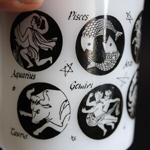 May include: White ceramic mug featuring black zodiac illustrations. The mug displays various zodiac signs like Aquarius, Pisces, Taurus, and Gemini. Each sign is within a black circle, with the sign's name below it.