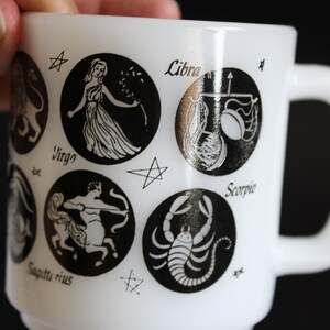May include: White ceramic mug featuring black zodiac symbols and star accents. The mug includes the signs Virgo, Libra, Scorpio, and Sagittarius. The mug has a white handle and a classic design.