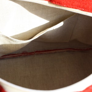 Puede incluir: El interior de una bolsa de lona blanca con forro rojo. La bolsa tiene un peque&ntilde;o bolsillo en el interior.