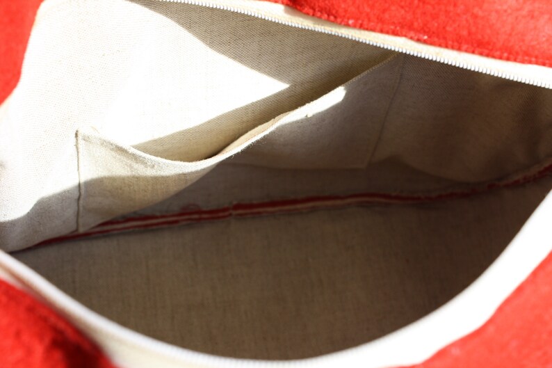 Puede incluir: El interior de una bolsa de lona blanca con forro rojo. La bolsa tiene un peque&ntilde;o bolsillo en el interior.