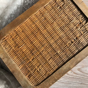 Puede incluir: Una bandeja de madera con un inserto de mimbre tejido. La bandeja tiene un marco de madera marr&oacute;n oscuro y el mimbre es de color marr&oacute;n claro.