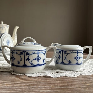 May include: Two white porcelain teacups with blue and white floral designs. The cups have a classic, vintage style.