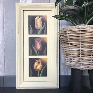 May include: A white framed picture with three panels featuring yellow, pink, and orange tulips on a black background.