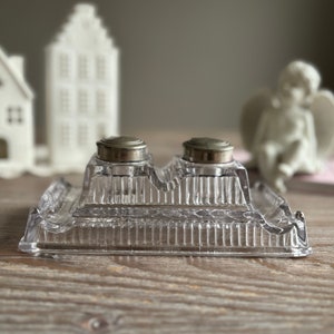 Op de afbeelding: Een set glazen inktpotten met twee inktpotten en een dienblad. De inktpotten hebben zilveren deksels en het dienblad heeft een decoratief patroon.