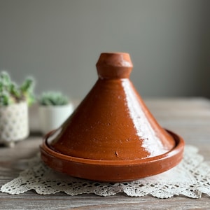 May include: A terracotta tagine with a domed lid, ideal for slow cooking. The tagine is glazed and has a rustic, handmade look.