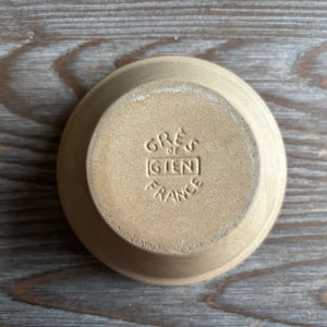 May include: A brown ceramic bowl with the words "GRES de GIEN FRANCE" stamped on the bottom.
