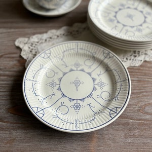 May include: A white ceramic plate with a blue and white floral design. The plate has a raised rim and a scalloped edge.