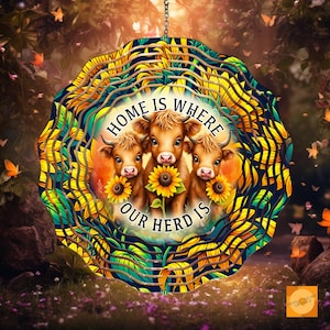 Peut inclure: Un mobile en métal avec un motif de tournesol. Le mobile représente trois vaches brunes et blanches avec le texte "Home is where our herd is".