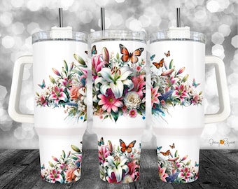 May include: White stainless steel tumbler with a floral design featuring lilies, butterflies, and pink flowers. The tumbler has a lid and a handle.
