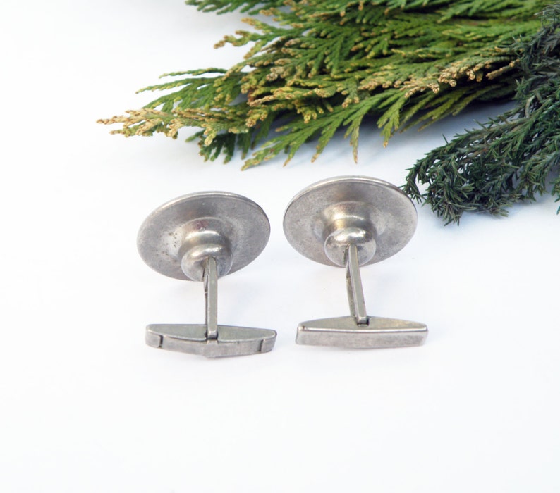 May include: A pair of silver cufflinks with a round, slightly domed design. The cufflinks have a simple, classic style.
