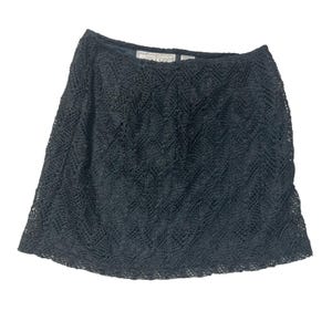 May include: A black, knee-length skirt with a crochet design. The skirt has a scalloped hemline and a fitted waist. The crochet pattern creates a textured appearance. The skirt is made of a lightweight material.