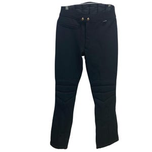 May include: Black ski pants with quilted knee and thigh panels. The pants have a high waist with two gold-colored buttons and a zipper closure. The pants are made of a smooth, matte fabric and have a slight flare at the bottom.