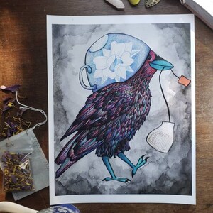 May include: A watercolor illustration of a crow wearing a blue teacup on its head. The crow is holding a tea bag in its beak and a tea strainer in its foot. The background is a dark gray watercolor wash.