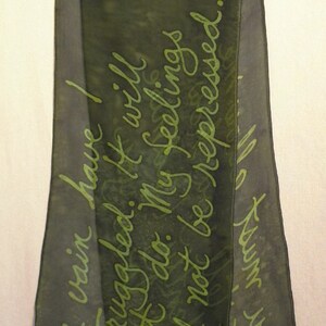 Puede incluir: Una bufanda de seda verde oscuro con un mensaje escrito a mano en tinta verde que dice "En vano he luchado. No servir&aacute; de nada. Mis sentimientos no ser&aacute;n reprimidos."