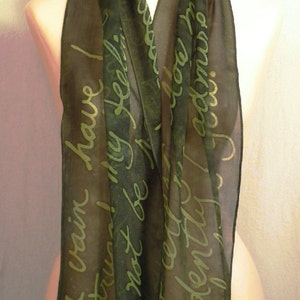 Puede incluir: Una bufanda de seda verde oscuro con fondo blanco y una cita manuscrita en letras verdes. La cita dice "En vano he luchado, mis sentimientos no pueden ser reprimidos, te adoro."