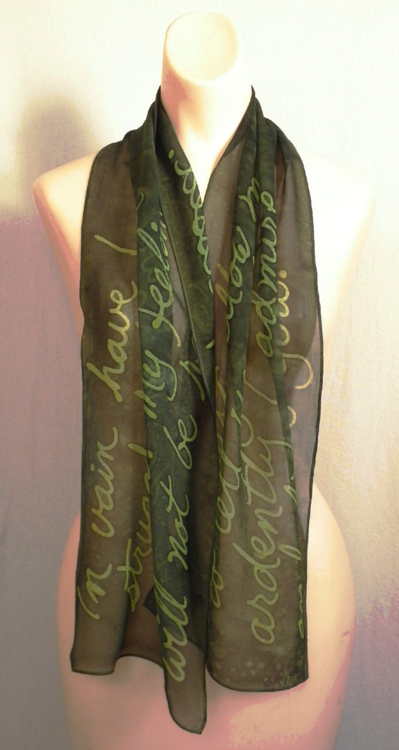 Puede incluir: Una bufanda de seda verde oscuro con fondo blanco y una cita manuscrita en letras verdes. La cita dice "En vano he luchado, mis sentimientos no pueden ser reprimidos, te adoro."