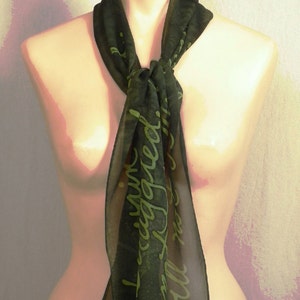 Puede incluir: Una bufanda de seda verde oscuro con una inscripci&oacute;n verde claro que dice "Estoy comprometida y no estoy estresada".