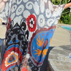 Op de afbeelding: Een doorschijnende, lichte kimono met een kleurrijk bloemenpatroon. De kimono is gemaakt van een doorschijnende stof en heeft een verscheidenheid aan kleuren, waaronder rood, blauw, geel en wit.