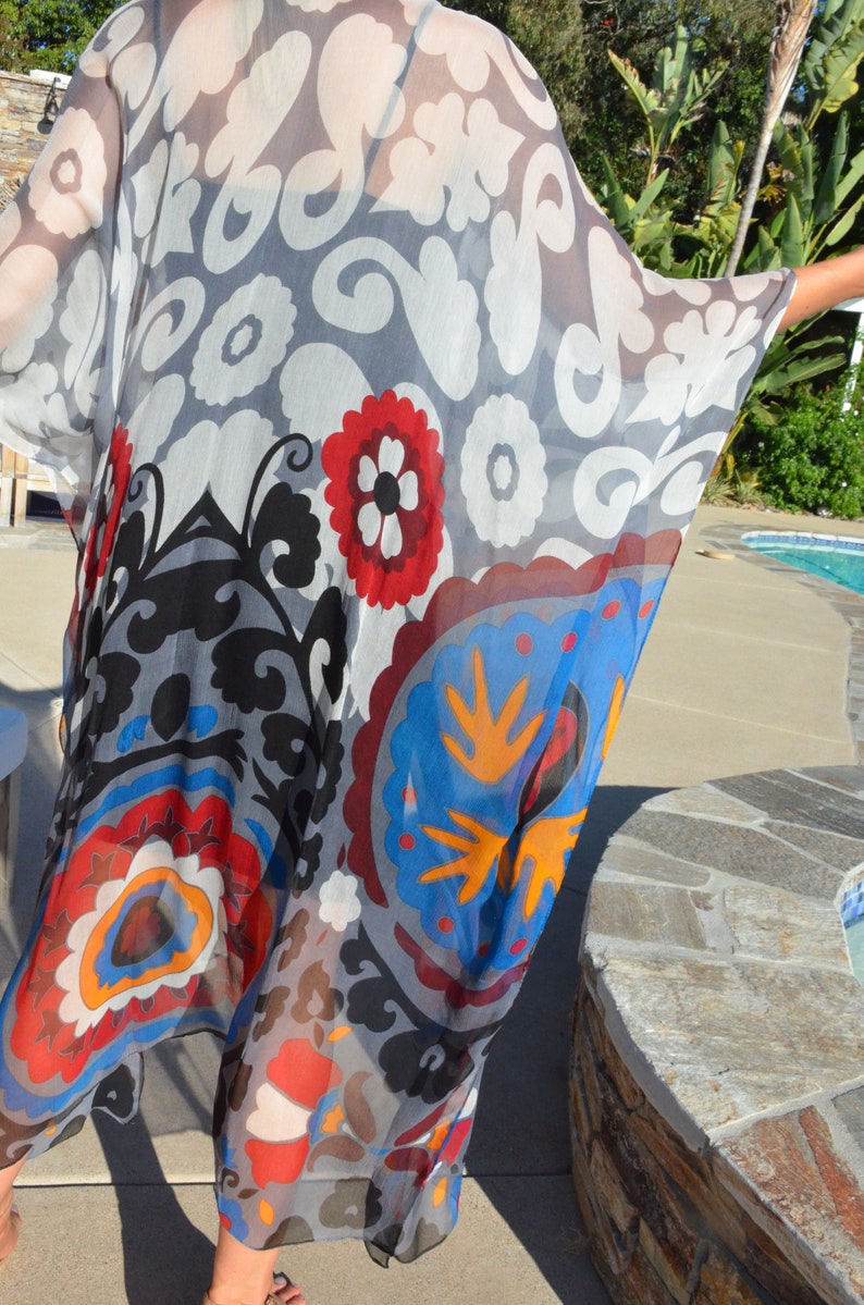 Op de afbeelding: Een doorschijnende, lichte kimono met een kleurrijk bloemenpatroon. De kimono is gemaakt van een doorschijnende stof en heeft een verscheidenheid aan kleuren, waaronder rood, blauw, geel en wit.