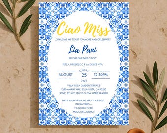 Puede incluir: Una invitación de boda con un diseño de azulejos azules y blancos, con el texto "Ciao Miss" en amarillo. La invitación incluye detalles del evento, rodeada de ramas de olivo y cerámica de terracota.