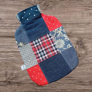 Könnte beinhalten: Eine Patchwork-Wärmflaschenhülle. Sie besteht aus verschiedenen Stoffen, darunter Jeansstoff, rote Punkte und Karomuster. Der obere Teil ist aus dunkelblauem Jeansstoff mit weißen Sternen. Das Design ist eine Mischung aus Mustern und Farben.