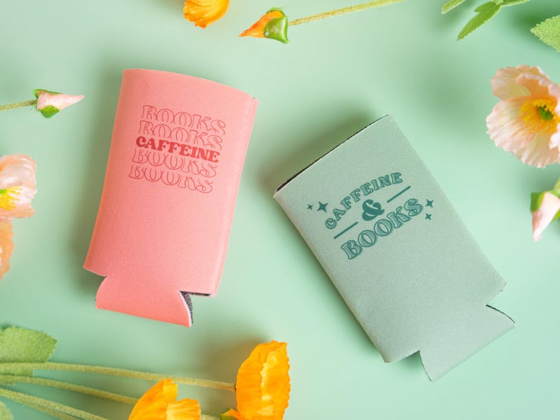 Op de afbeelding: Twee drankisolatoren, &eacute;&eacute;n koraal en &eacute;&eacute;n zeegroen, liggen op een lichtgroen oppervlak. Op de koraal isolator staat de tekst "BOOKS CAFFEINE BOOKS BOOKS". Op de zeegroene isolator staat de tekst "CAFFEINE & BOOKS".