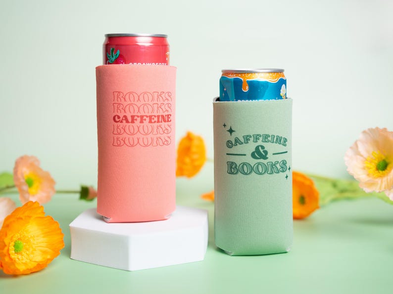 Op de afbeelding: Twee blikjeskoelers, &eacute;&eacute;n koraal en &eacute;&eacute;n mintgroen, elk met een blikje. De koraalkoeler heeft de tekst "BOOKS CAFFEINE BOOKS" in een retro lettertype. De mintgroene koeler heeft de tekst "CAFFEINE & BOOKS."