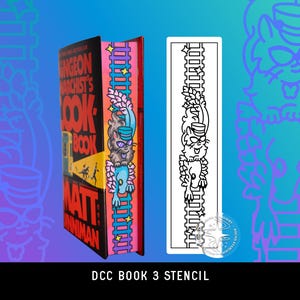 May include: A book titled Dungeon Crawler Carl's Cookbook by Matt Dinniman with a colorful cat illustration on the page edges, displayed next to a matching black and white rectangular stencil featuring the same cat and ladder design.