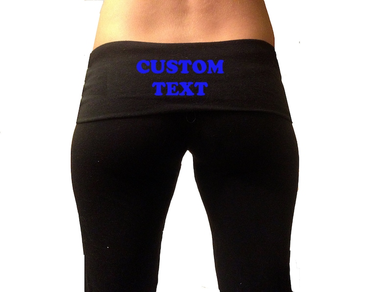 Op de afbeelding: Zwarte yogabroek met een zwarte tailleband waarop de tekst "CUSTOM TEXT" in het blauw staat.