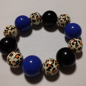 May include: A bracelet made of colorful beads. The beads are blue, black, and white with a leopard print pattern.