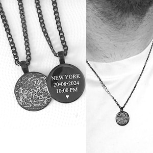 May include: Two black circular pendants on matching black chains. One pendant features a white celestial star map grid. The other pendant displays the white text NEW YORK, 20.08.2024, 10:00 PM, and a small heart symbol. The pendants have a glossy finish.