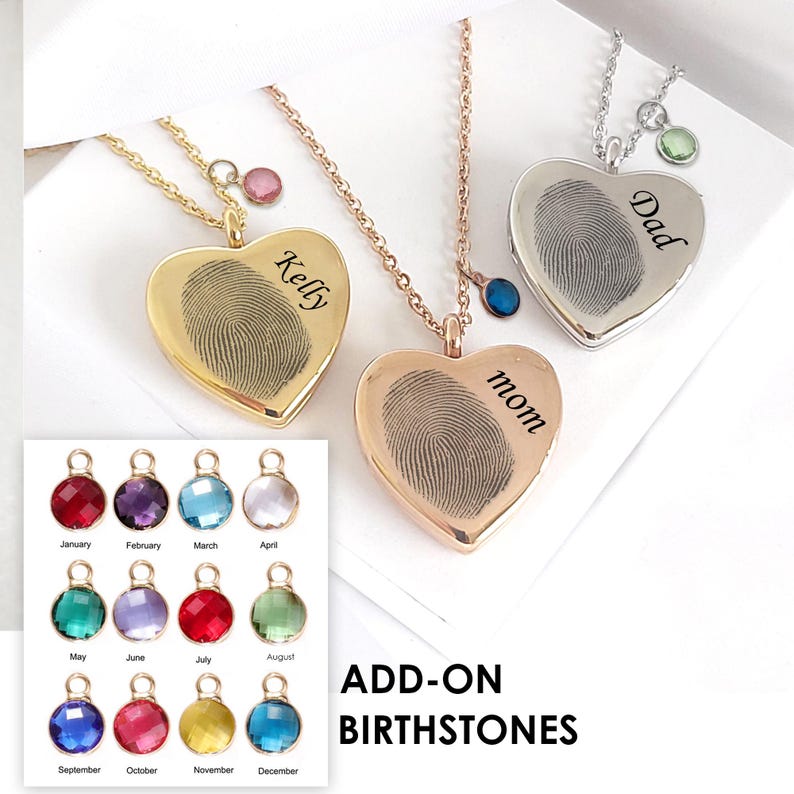 May include: Three heart-shaped pendants on chains, in gold, rose gold, and silver tones. Each pendant features a black fingerprint engraving and a name: Kelly, mom, and Dad. A chart displays twelve colourful circular birthstone charms.