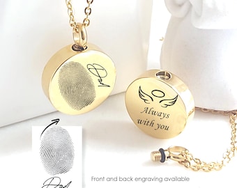 May include: A gold-toned circular pendant necklace featuring a fingerprint engraving and the word Dad on the front. A second matching pendant shows an angel wing graphic with the text Always with you. The set includes a delicate gold chain.