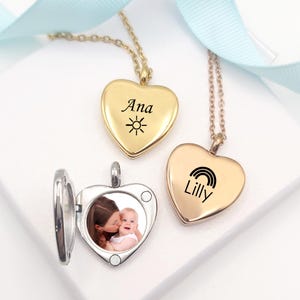 May include: Three gold-toned heart-shaped lockets on delicate chains. Two lockets are closed, one engraved with the name Ana and a sun icon, the other with the name Lilly and a rainbow icon. A third locket is open, revealing a photograph of a person.