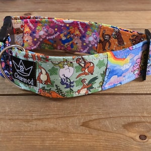 May include: A colorful dog collar with a black buckle and a silver metal ring. The collar features a patchwork design with cartoon characters, rainbows, and the word "Charmed" on a black label.