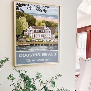 May include: Framed print of Cousins Beach, Massachusetts, featuring a large house, trees, and a beach scene. The print has a light blue and beige color scheme, with the text "Cousins Beach Massachusetts" at the bottom.