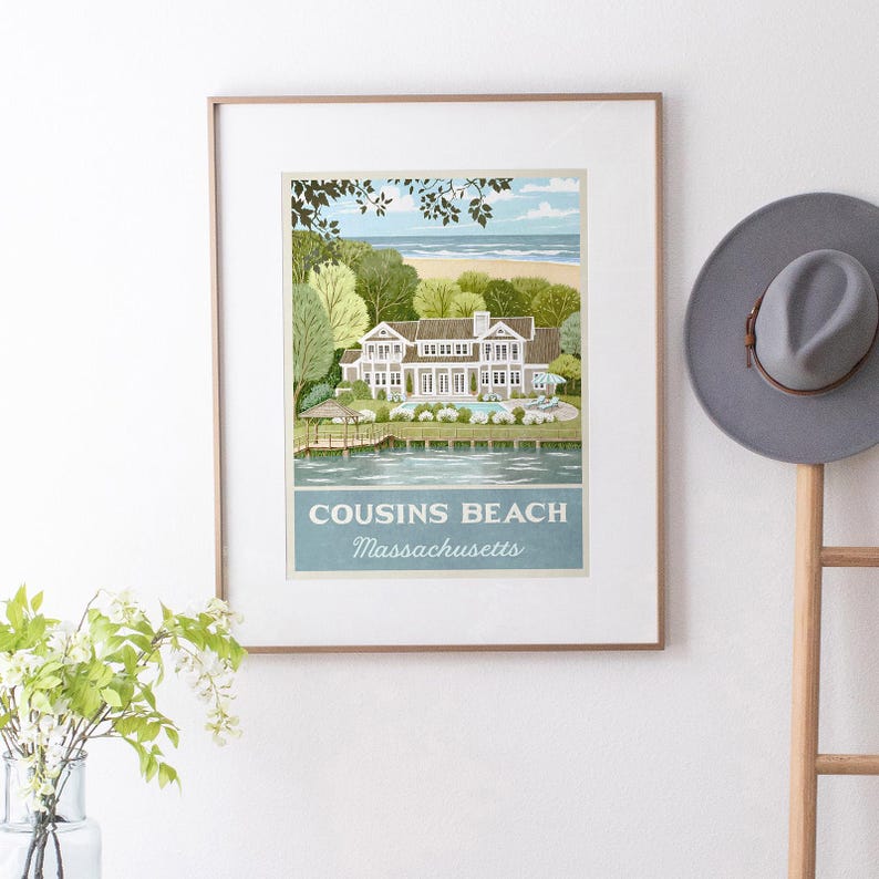 May include: Framed art print featuring a coastal scene with a large white house, trees, and a beach. The print includes the text "COUSINS BEACH Massachusetts" in a blue banner. A gray hat hangs on a wooden rack to the right.