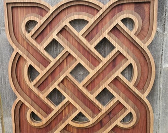 May include: A wooden Celtic knot wall art with a brown and reddish-brown color scheme. The knot is intricately carved and has a layered design.