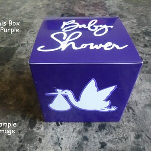 Puede incluir: Caja de regalo morada con la inscripción "Baby Shower" en blanco y una silueta blanca de una cigüeña llevando un bebé.