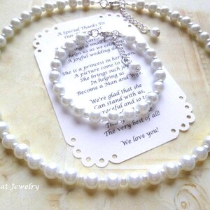 May include: A white pearl necklace and matching bracelet set. The jewelry is displayed on a decorative card with text. The necklace and bracelet are made of round, white pearls and silver-toned clasps.