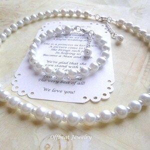 May include: A white pearl necklace and matching bracelet set. The jewelry is displayed on a white card with text. The necklace and bracelet are made of round, white pearls and have silver-colored clasps.