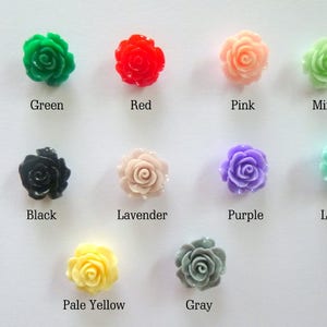 Op de afbeelding: Assortiment van tien kleine plastic roosvormige versieringen in verschillende kleuren, waaronder groen, rood, roze, mint, zwart, lavendel, paars, lichtblauw, lichtgeel en grijs.