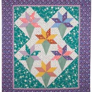 Pode incluir: Uma colcha artesanal com uma borda floral e um design central de estrelas coloridas. As estrelas são em tons de laranja, rosa, azul e amarelo, sobre um fundo branco com detalhes verdes. A colcha mede aproximadamente 152 cm por 178 cm.