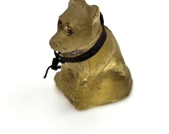 May include: A small, light brown glass figurine of a sitting cat with a black ribbon around its neck.