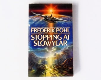 May include: A paperback book cover with a blue and orange background. The title is "Stopping at Slowyear" by Frederik Pohl, author of Gateway. The cover features a spaceship flying over a planet.