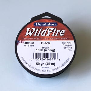 May include: A spool of black WildFire thermally bonded bead weaving thread. The label includes the text ".006 in 0.15 mm", "Break 10 lb (4.5 kg)", and "50 yd (45 m)". The product is intended for adult use.