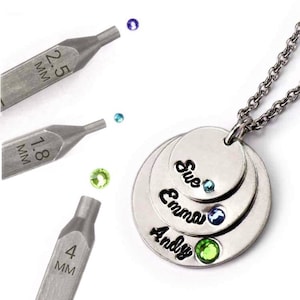 May include: Silver necklace with three layered discs engraved with the names Sue, Emma, and Andy. Each disc has a small gemstone set in the center. The gemstones are blue, blue, and green. The necklace is shown with three different sized tools for setting gemstones.