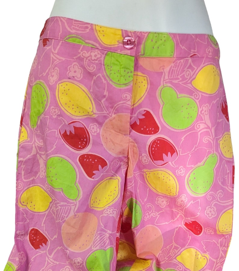 K&ouml;nnte beinhalten: Rosa Baumwollshorts mit einem Zitronen- und Erdbeerprint. Die Shorts haben einen Knopfverschluss und einen rosa Bund.